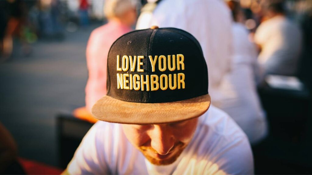 A man wearing a "love your neighbour" cap