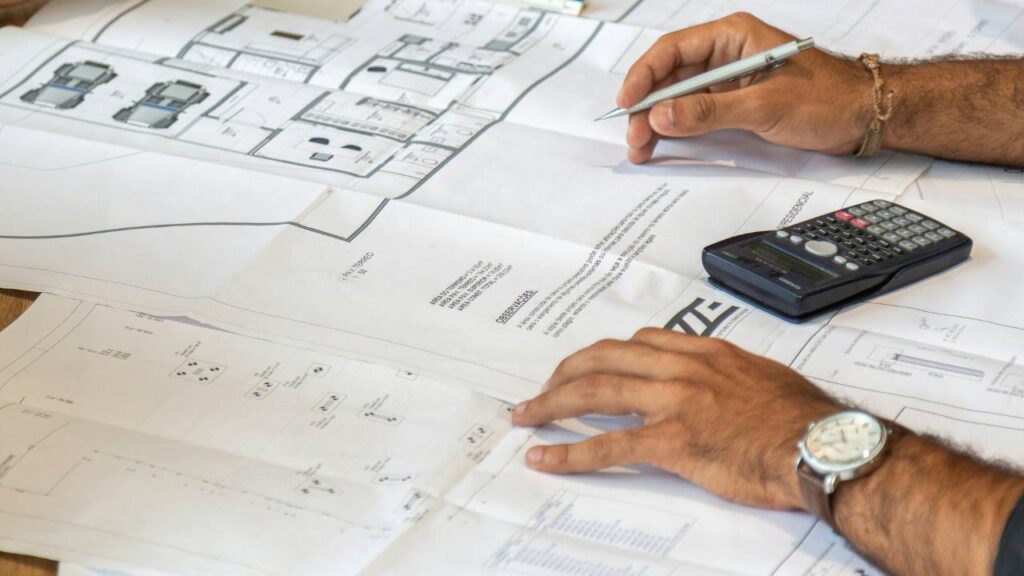 A photo of a man's hands on papers with construction plans