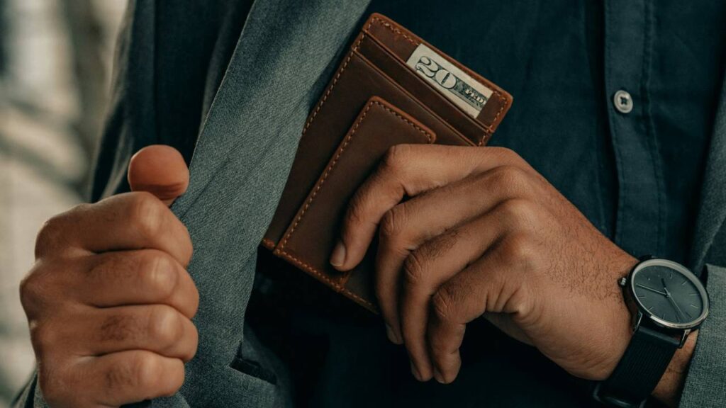 A businessman putting a leather wallet into the pocket of his suit