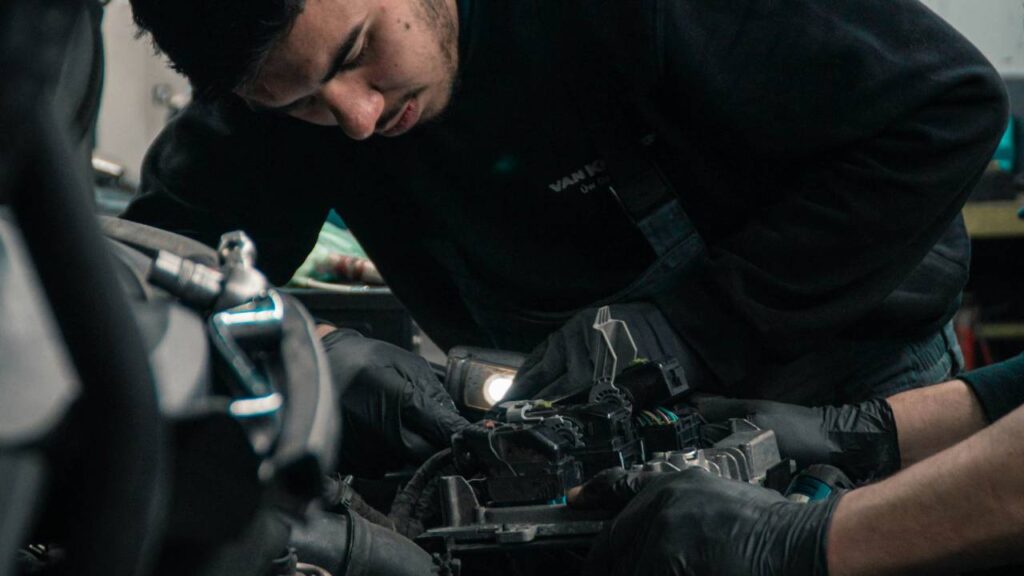 A man in the process of repairing an engine of an automobile