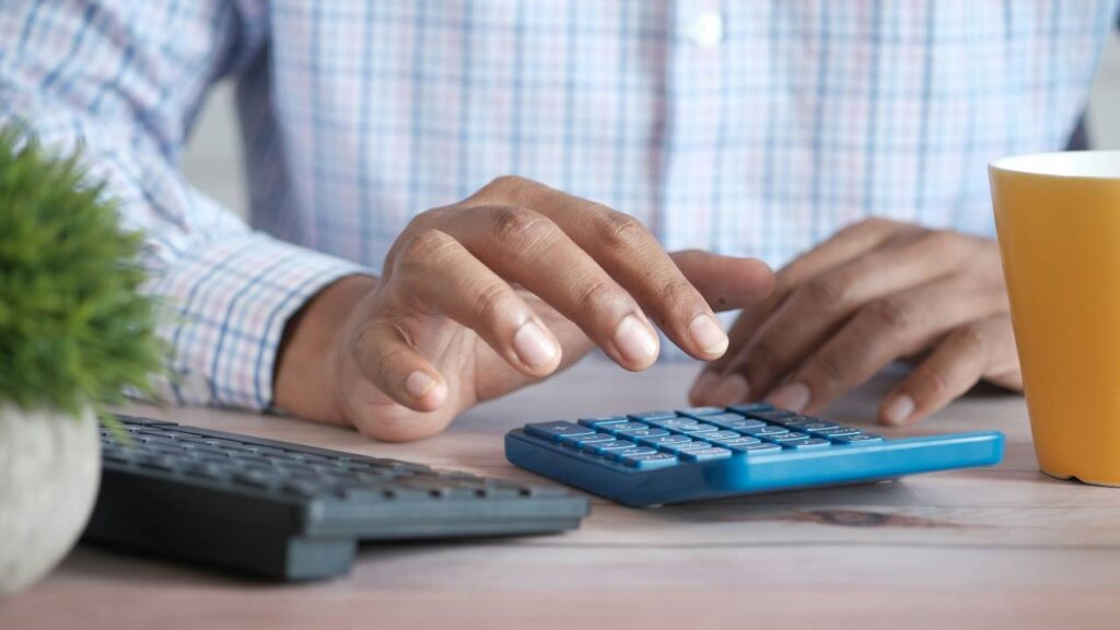 A close-up photo of a man using a blue calculator