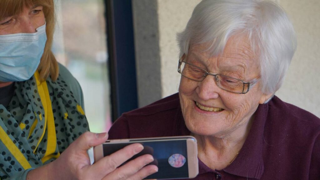 A woman showing an older woman something on her smartphone