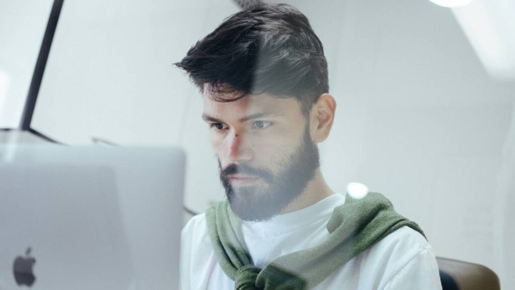 A man with a beard using an Apple computer