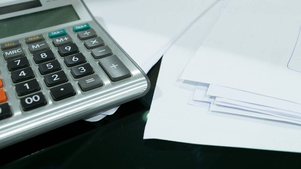 An old calculator next to a stack of documents