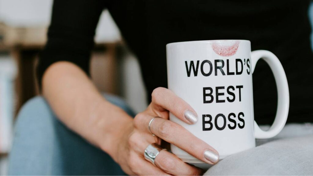 A close-up photo of a woman's hand on a coffee cup with "world's best boss" written on it 