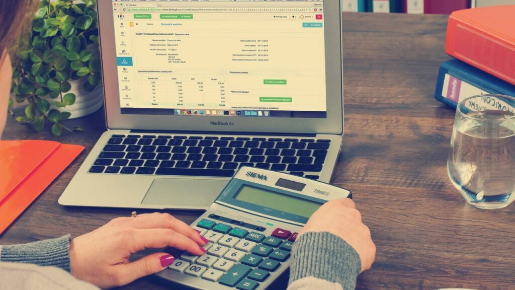 A woman using a laptop and a calculator at the same time